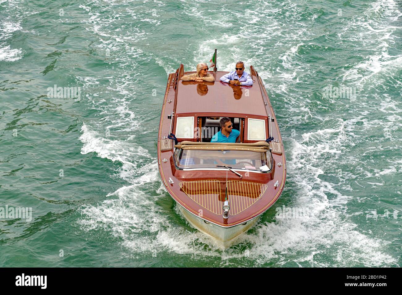 A water taxi with two passengers standing at the rear of the boat looking at the view ,Venice,Italy Stock Photo