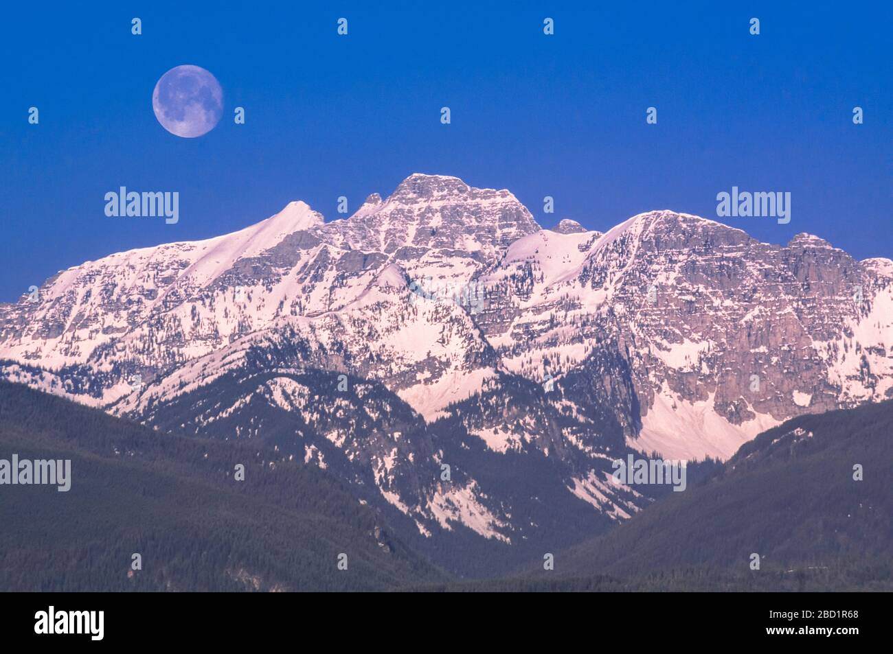 moon over peaks of the mission range above elk creek valley near condon, montana Stock Photo