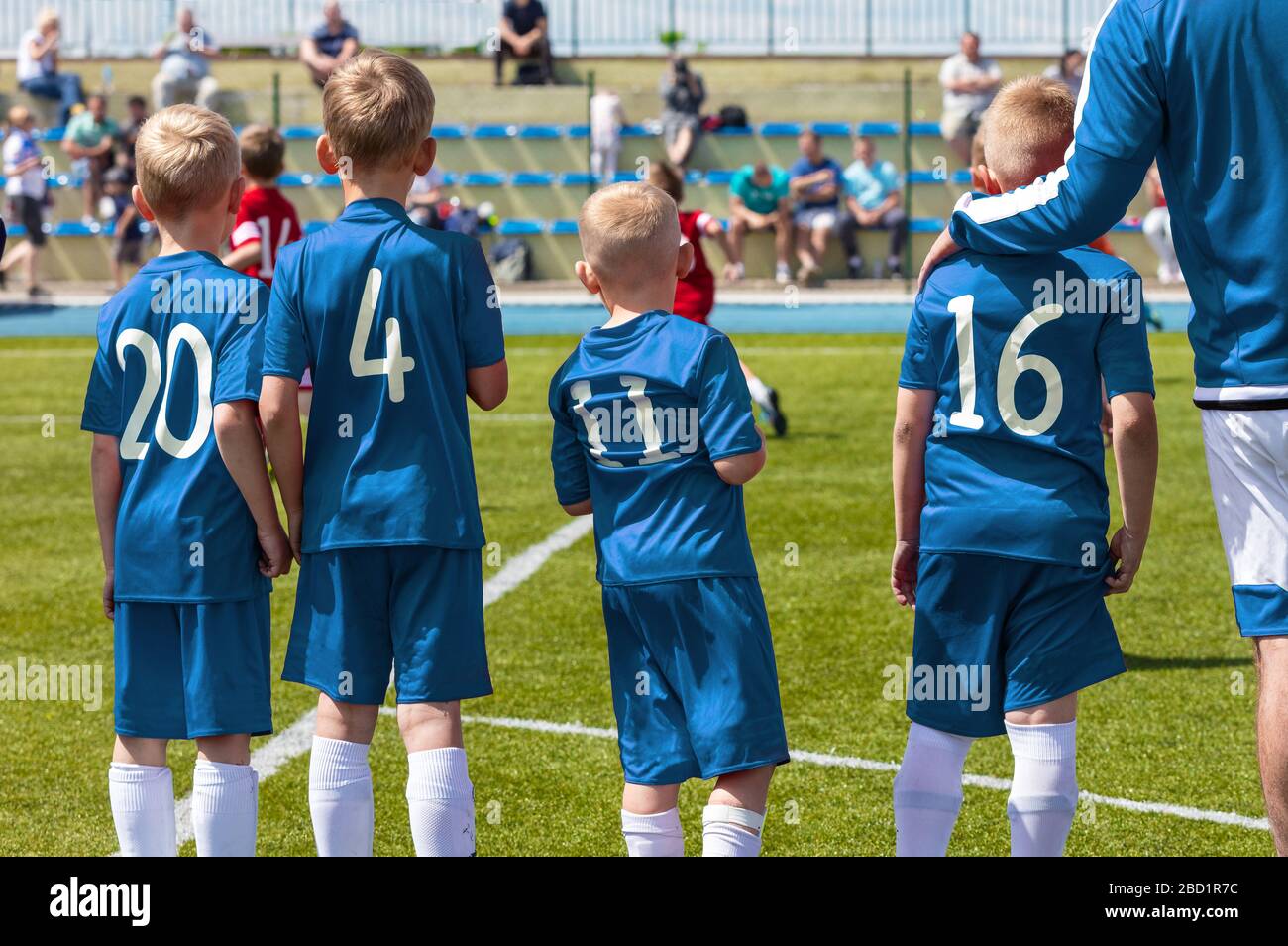 Group of Junior Sports Soccer Player Standing with Coach on Sideline. Soccer Team Substitute Players. Coach of Youth Football Team Picking Boy Ready t Stock Photo