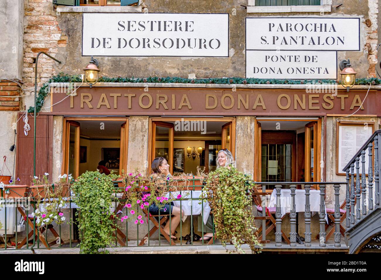 Two woman sitting at a table outside Trattoria Dona Onesta an Italian restaurant in the Dorsoduro district of Venice,Italy Stock Photo