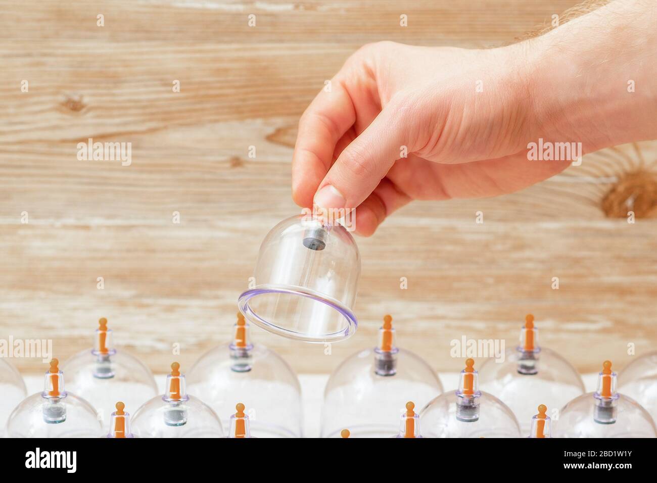 Hand takes vacuum massage glass jar from medical set of traditional Chinese cupping therapy