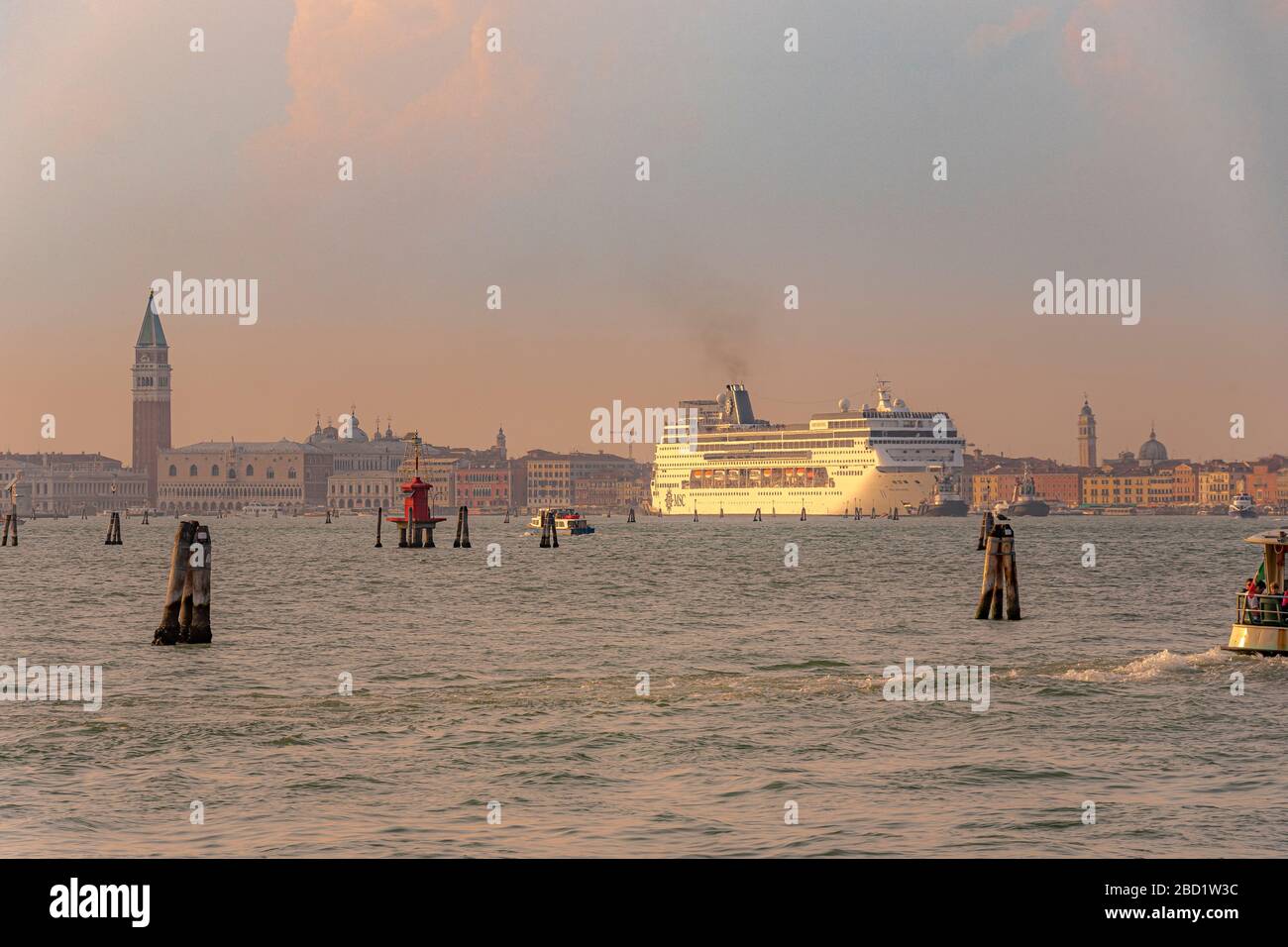 A large cruise ship makes it's way through the Venice Lagoon,with St Mark's Campanile or bell tower in the distance, Venice,Italy Stock Photo