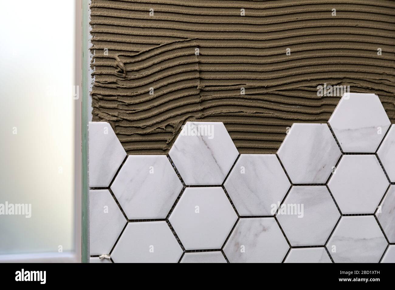 tiling - laying white marble texture hexagon tiles on the wall Stock Photo