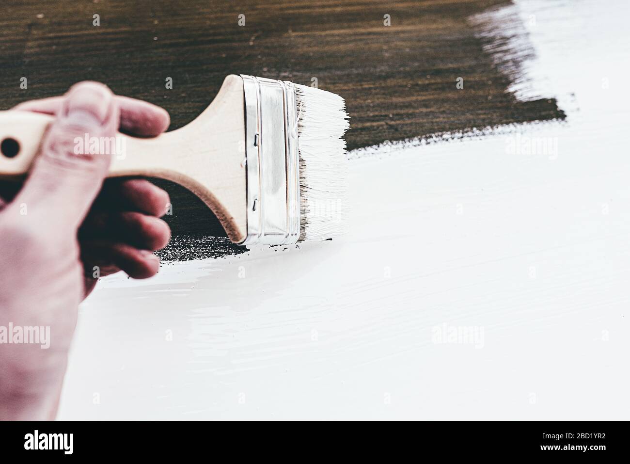 close-up of hand using brush to lacquer wooden furniture with white paint Stock Photo