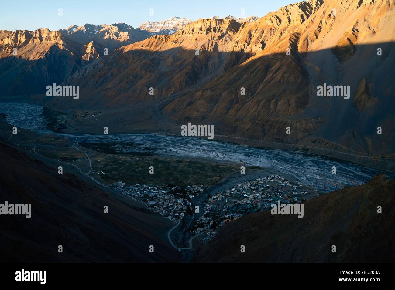 Beautiful river flows past small town in deep valley flanked by Himalayas near Kaza, Himachal Pradesh, India. Stock Photo