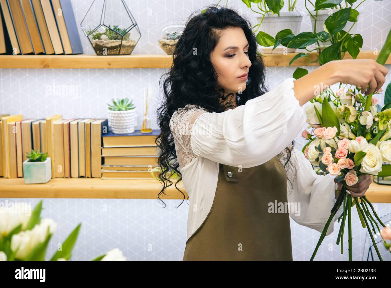 Attractive young woman florist is working in a flower shop Stock Photo ...