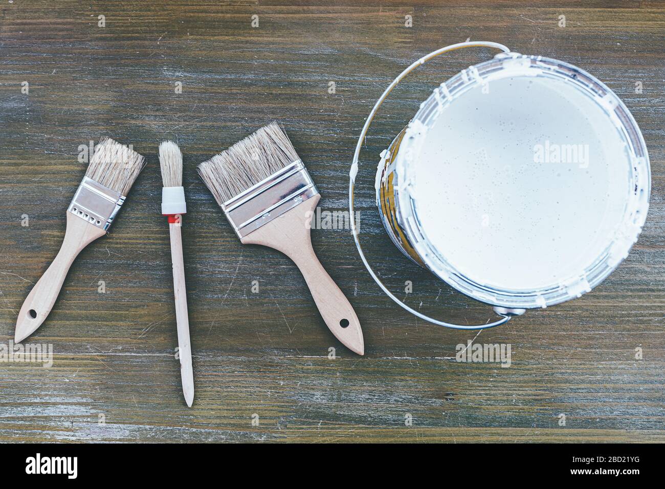 top view of different paint brushes and white paint on wooden surface, home improvement concept Stock Photo