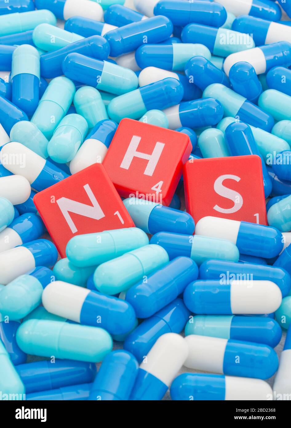 NHS letters tiles sinking into pills. For NHS overwhelmed by Covid 19 pandemic, NHS heroes, National Health Service, NHS struggling under covid cases Stock Photo