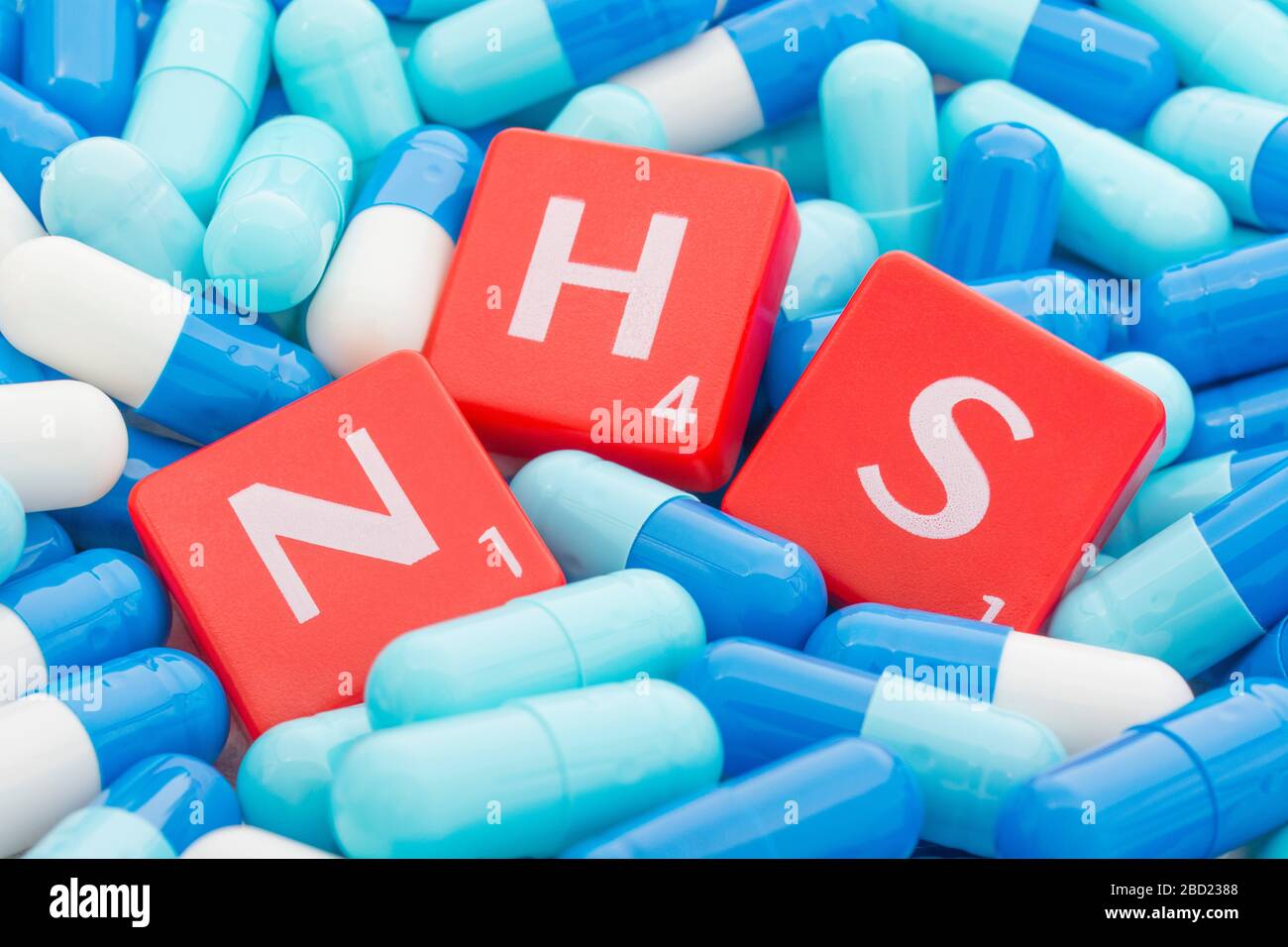 NHS letters tiles sinking into pills. For NHS overwhelmed by Covid 19 pandemic, NHS heroes, National Health Service, NHS struggling under covid cases Stock Photo