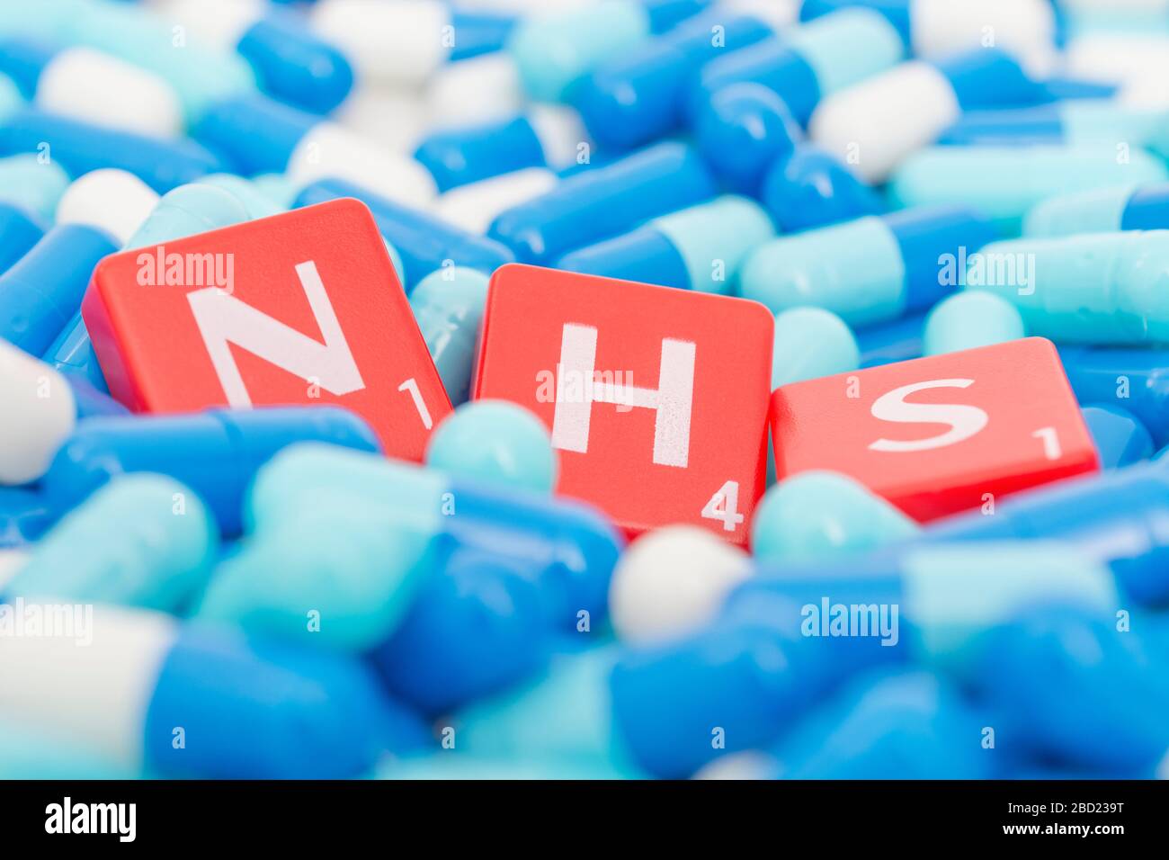 NHS letters tiles sinking into pills. For NHS overwhelmed by Covid 19 pandemic, NHS heroes, National Health Service, NHS struggling under covid cases Stock Photo