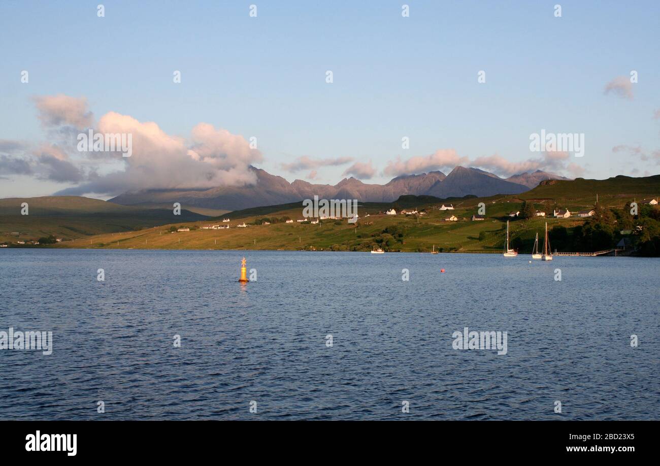 The Cuillins and Carbost village from Loch Harport near Talisker distillery, Isle of Skye, Hebrides, Scotland Stock Photo