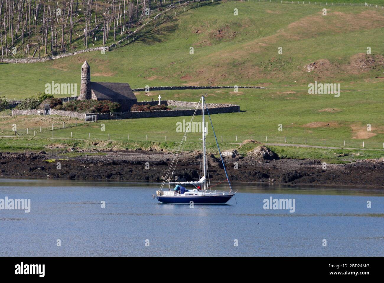 Sailing yacht anchored in Canna harbour, and the church, Canna, Hebrides, Scotland Stock Photo