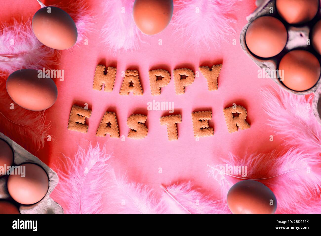 Closeup beautiful lettering of happy Easter cookie letters on a pink background with eggs, top view Stock Photo