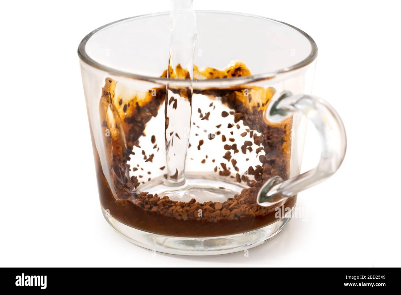 Pouring hot water onto instant coffee in grass mug isolated on white. Partially dissolved coffee. Stock Photo