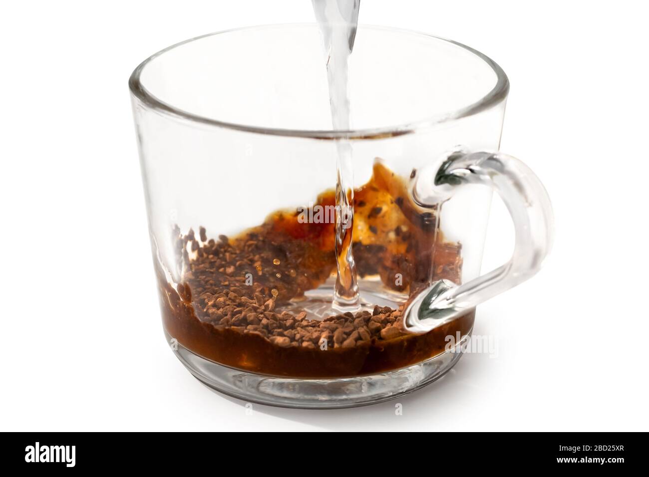 Pouring hot water onto instant coffee in grass mug isolated on white