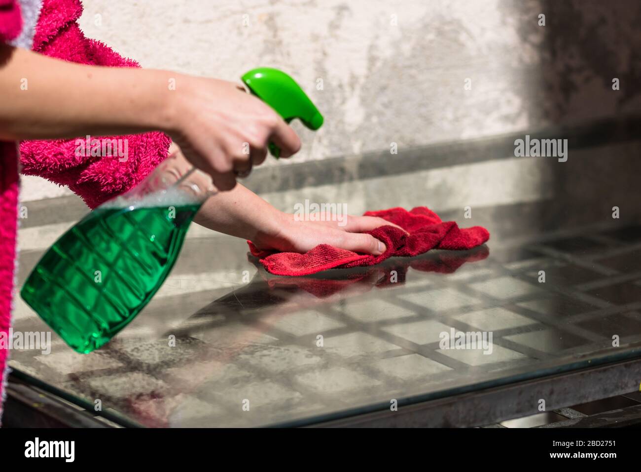 Woman cleaning glass table red microfiber rug and cleaning sprayer, cleaning services concept