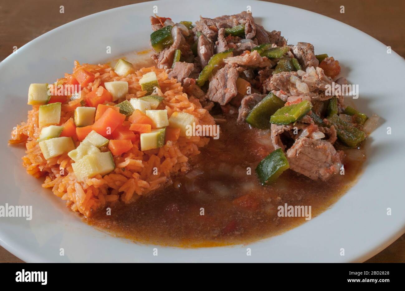 Mexican food ranchero beef steak with chile and Mexican rice on the side with vegetables on top of the rice spicy dish ranch beef steak Stock Photo