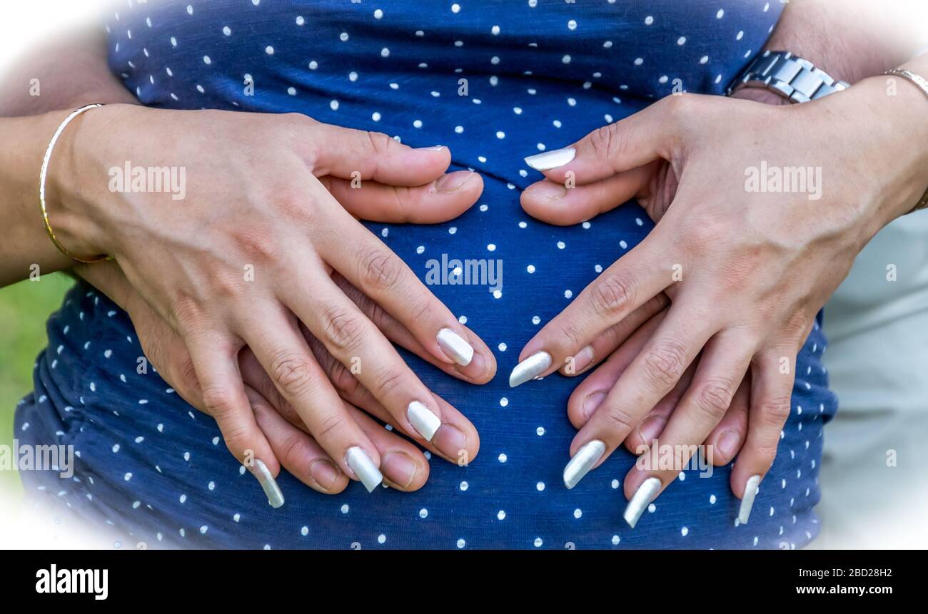 Man and Woman's hands together at the belly of their unborn child Stock Photo