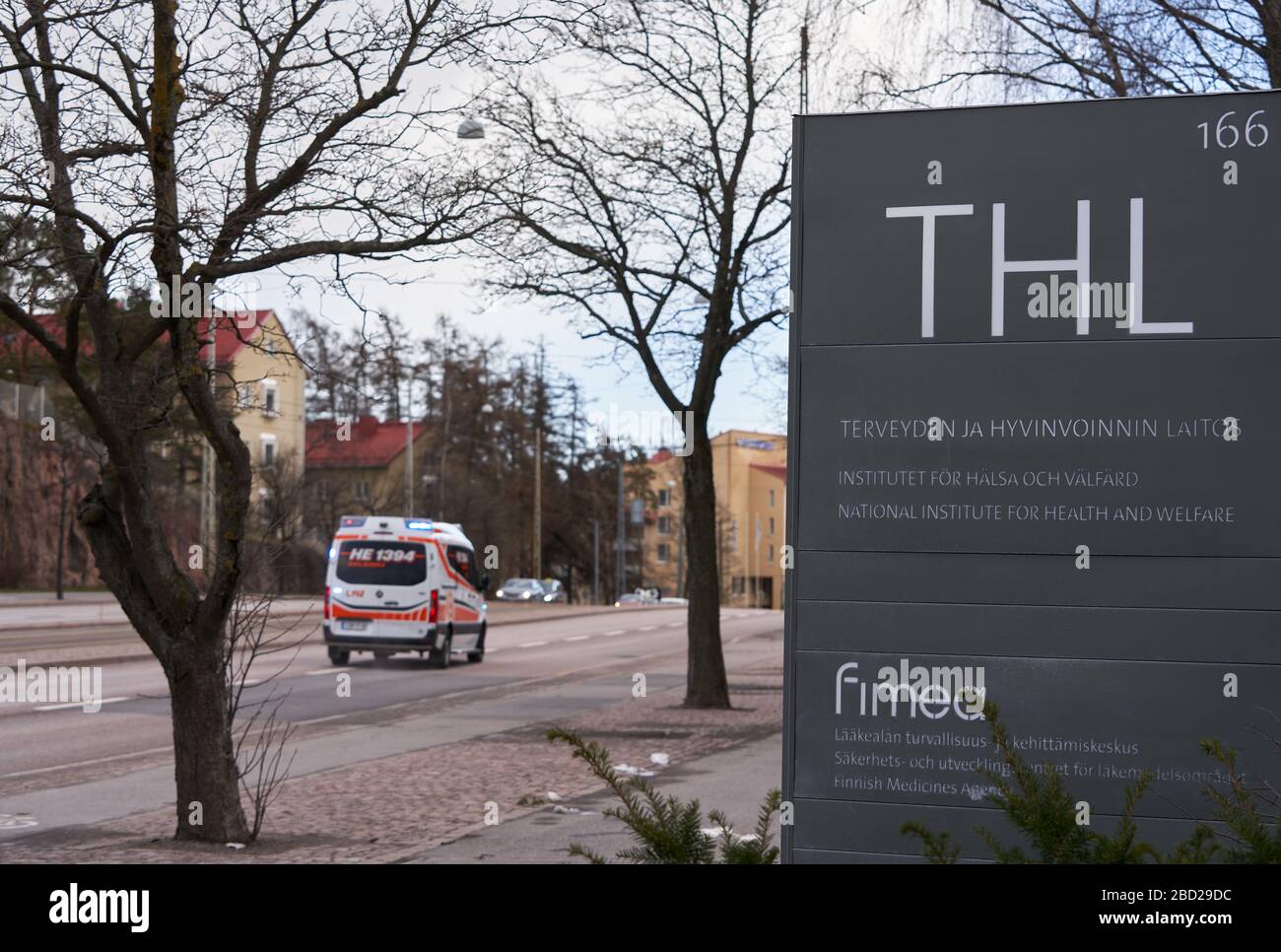 Helsinki, Finland - April 4, 2020: Outdoors sign of the (Finnish) National Institute for Health and Welfare (THL) with an ambulance passing on Mannerh Stock Photo