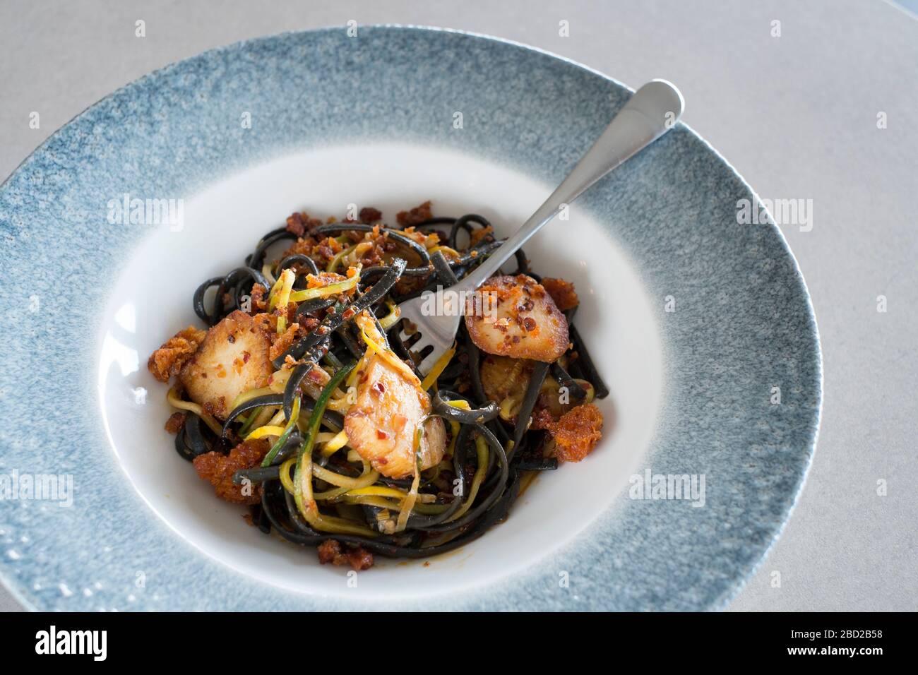 Squid ink linguine with Cornish scallops & Nduja pangrattato, cooked by chef Andy Appleton Stock Photo