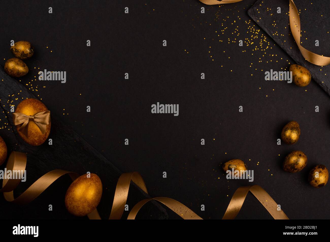 Golden luxury easter eggs and ribbon composition boder frame on black stone background with copy space for text card Stock Photo