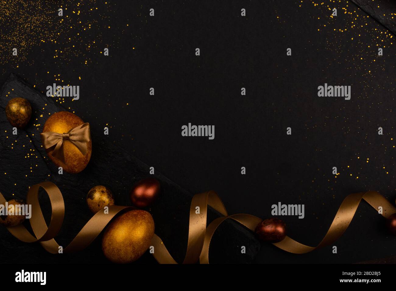 Golden luxury easter eggs and ribbon composition boder frame on black stone background with copy space for text card Stock Photo