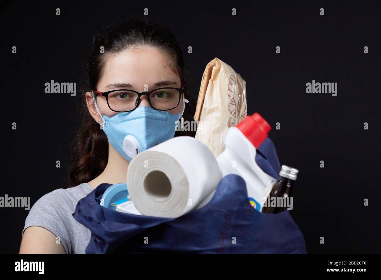 Young woman in a valve of the respiratory protective mask with a bag full of groceries from the supermarket. concept covidiots. Stock Photo