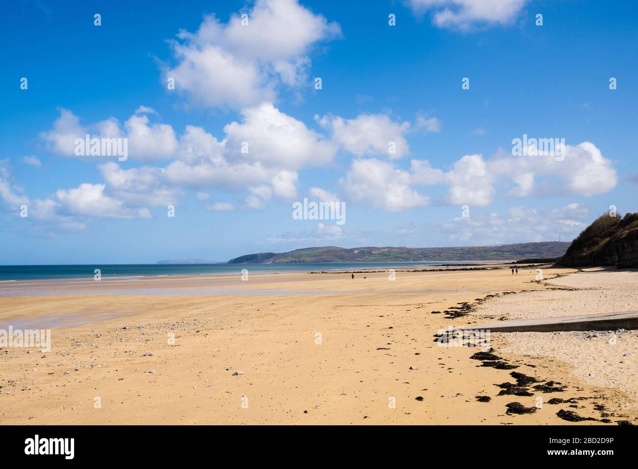 Large expanse of quiet beach with a few local people walking for daily exercise during Covid-19 lockdown in April 2020. Benllech Anglesey Wales UK Stock Photo