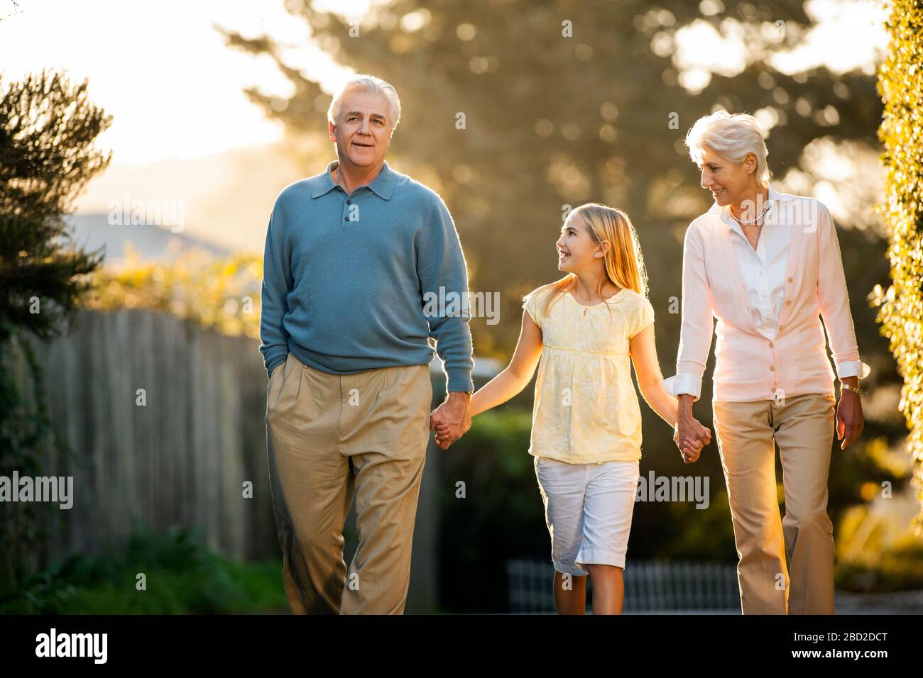 Mature couple walking hand in hand with their young granddaughter. Stock Photo