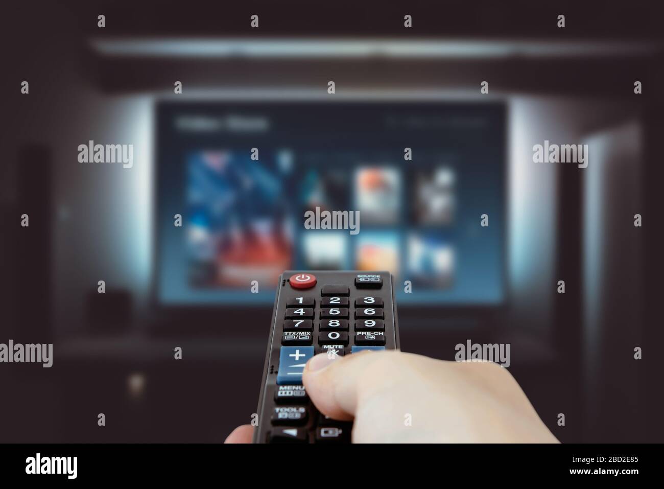 VOD service on television. Man watching TV, streaming service, video on demand, remote control in hand. Stock Photo