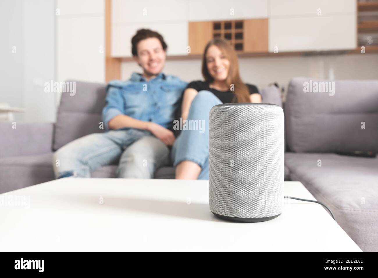 Couple talking command to smart speaker. Intelligent assistant in smart home system. Stock Photo