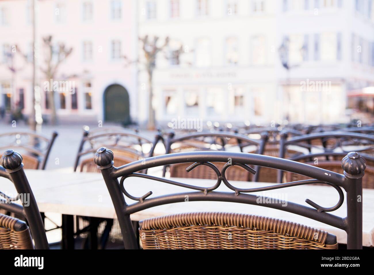 Empty restaurant or cafe with tables and chairs  because of coronavirus crisis in a historical city enter - focus on the foreground Stock Photo