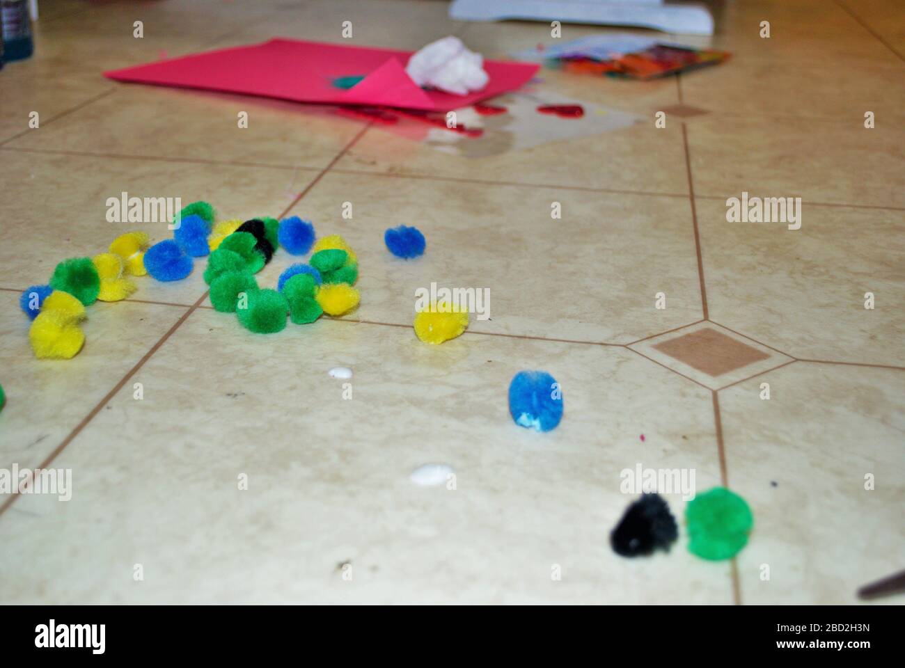 Multi colored cotton balls and glue on a linoleum floor during arts and