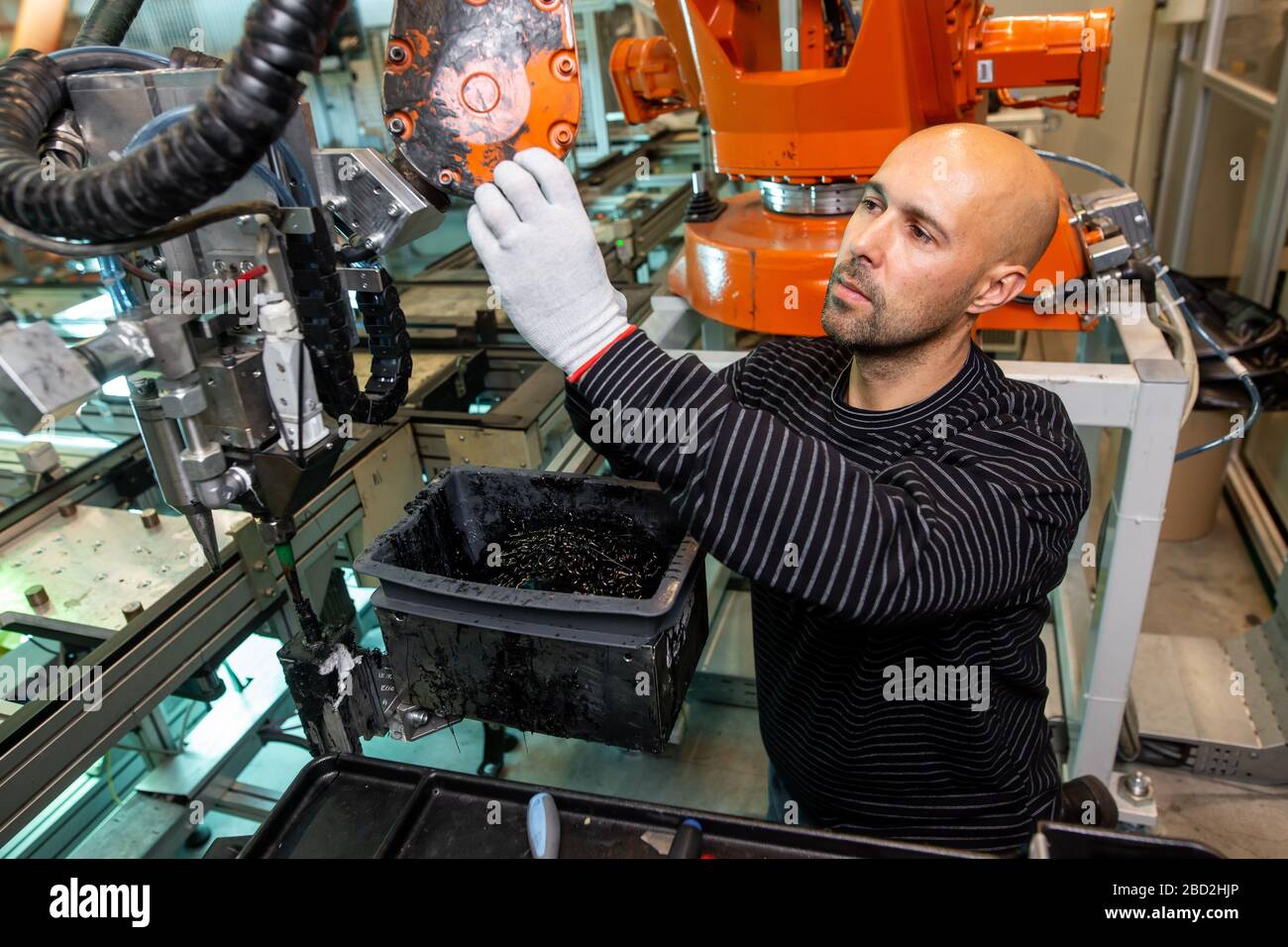 Engineer optimizing production by robotic arm in automotive smart factory, employee in industry, industrial concept Stock Photo