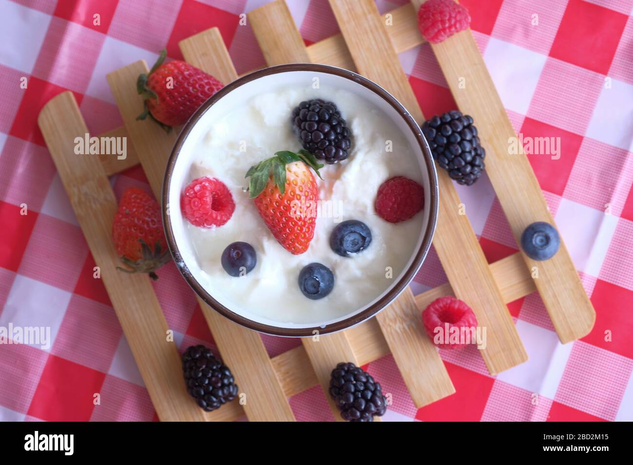 Bowl of fresh mixed berries and yogurt on table Stock Photo