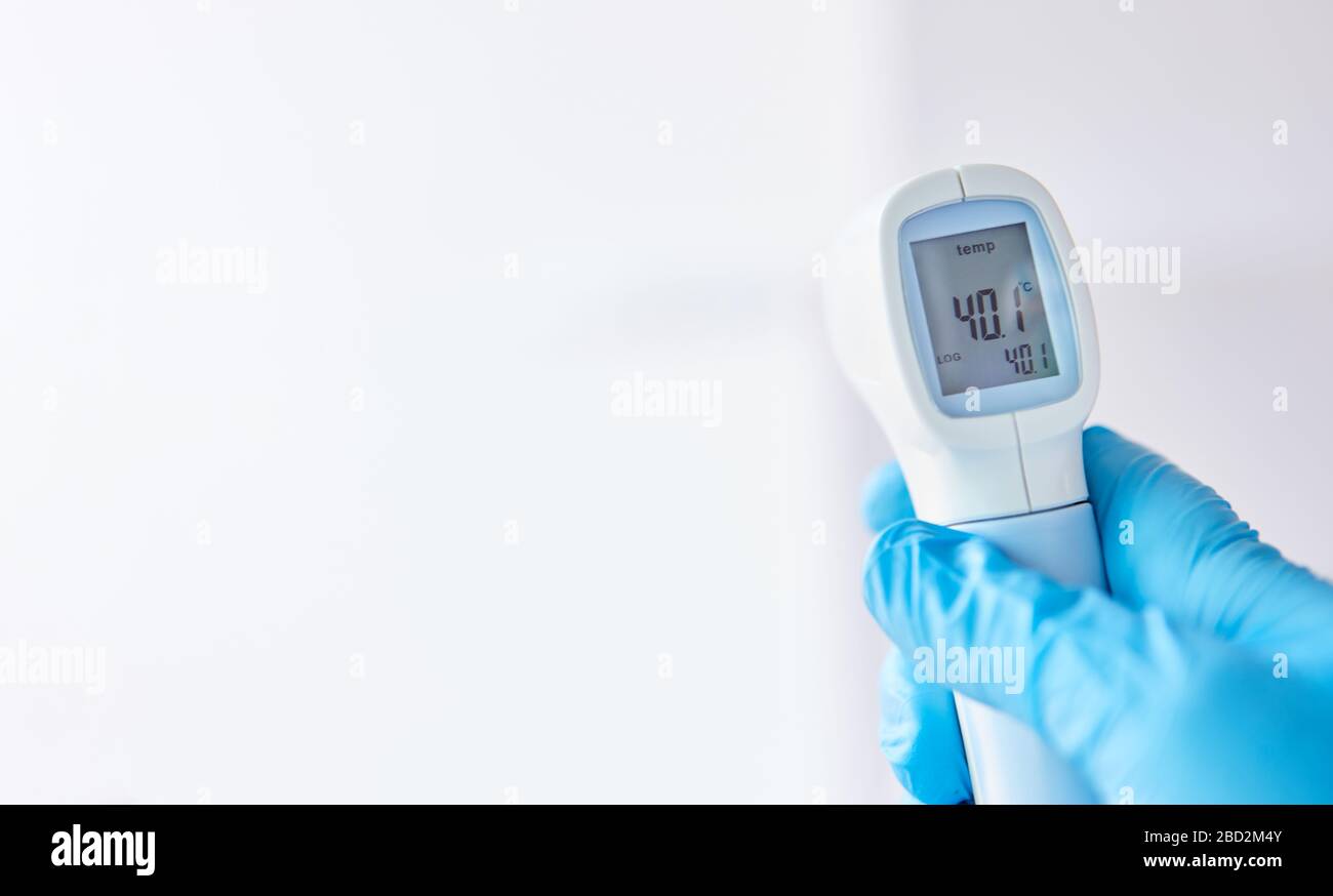 Infrared clinical thermometer shows fever after measurement in Covid-19 coronavirus epidemic Stock Photo
