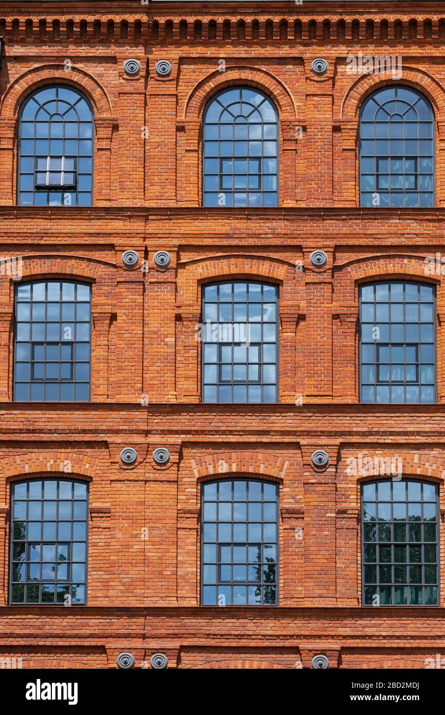 Red brick classic industrial building facade with multiple windows background. Stock Photo