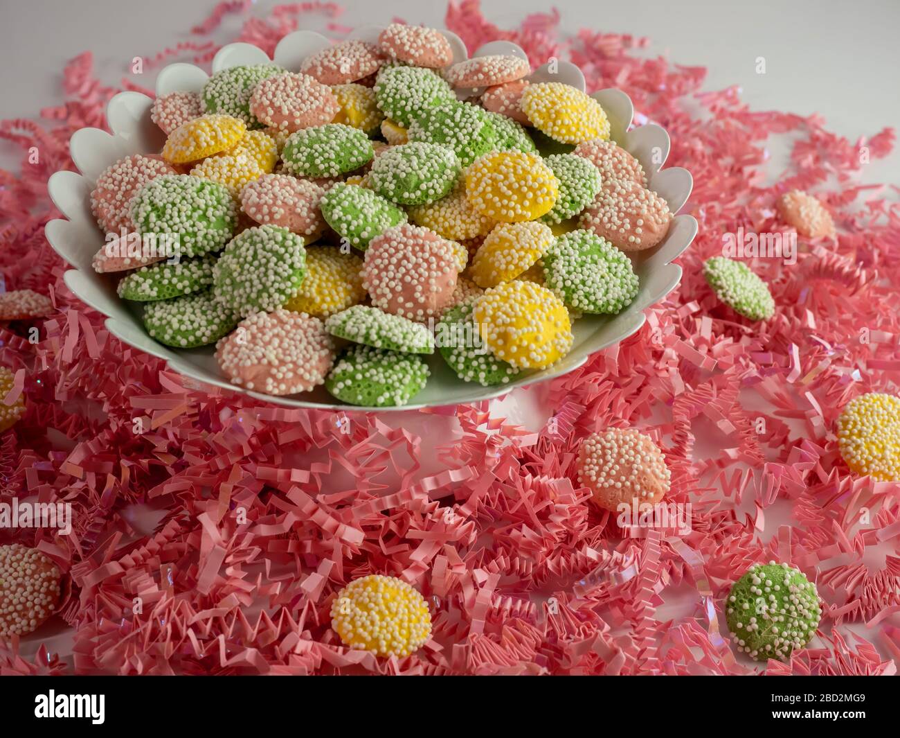 Pastel colored round candies coated with white dot sprinkles in a