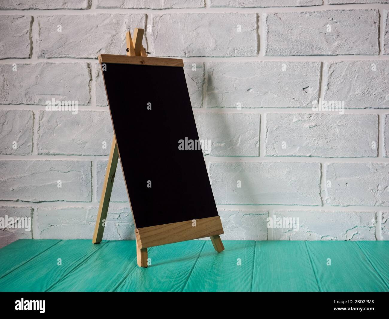 easel black against a brick wall, mockup empty space for design Stock Photo