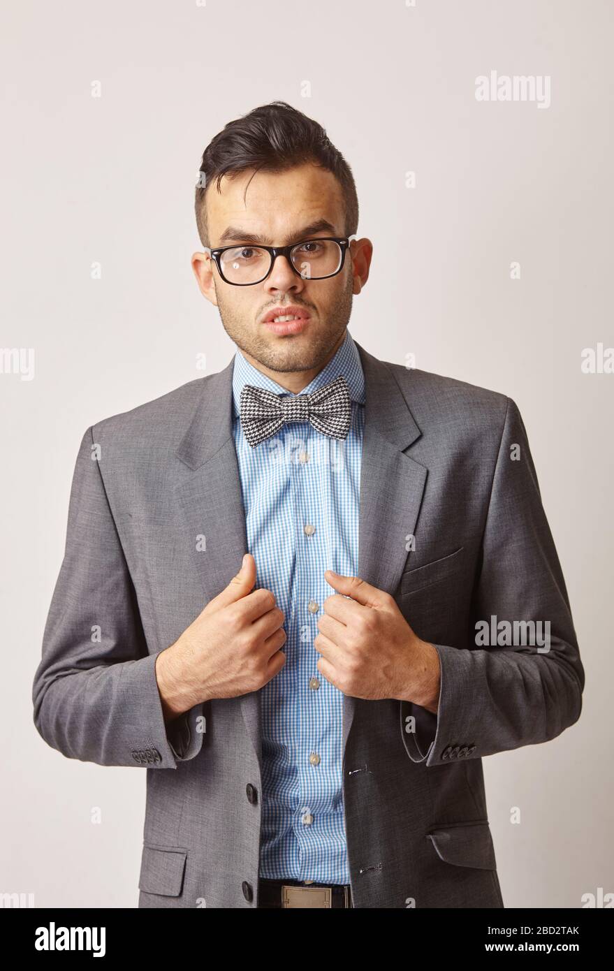 studio portrait of a young man in a blue shirt with a butterfly and glasses. Stock Photo