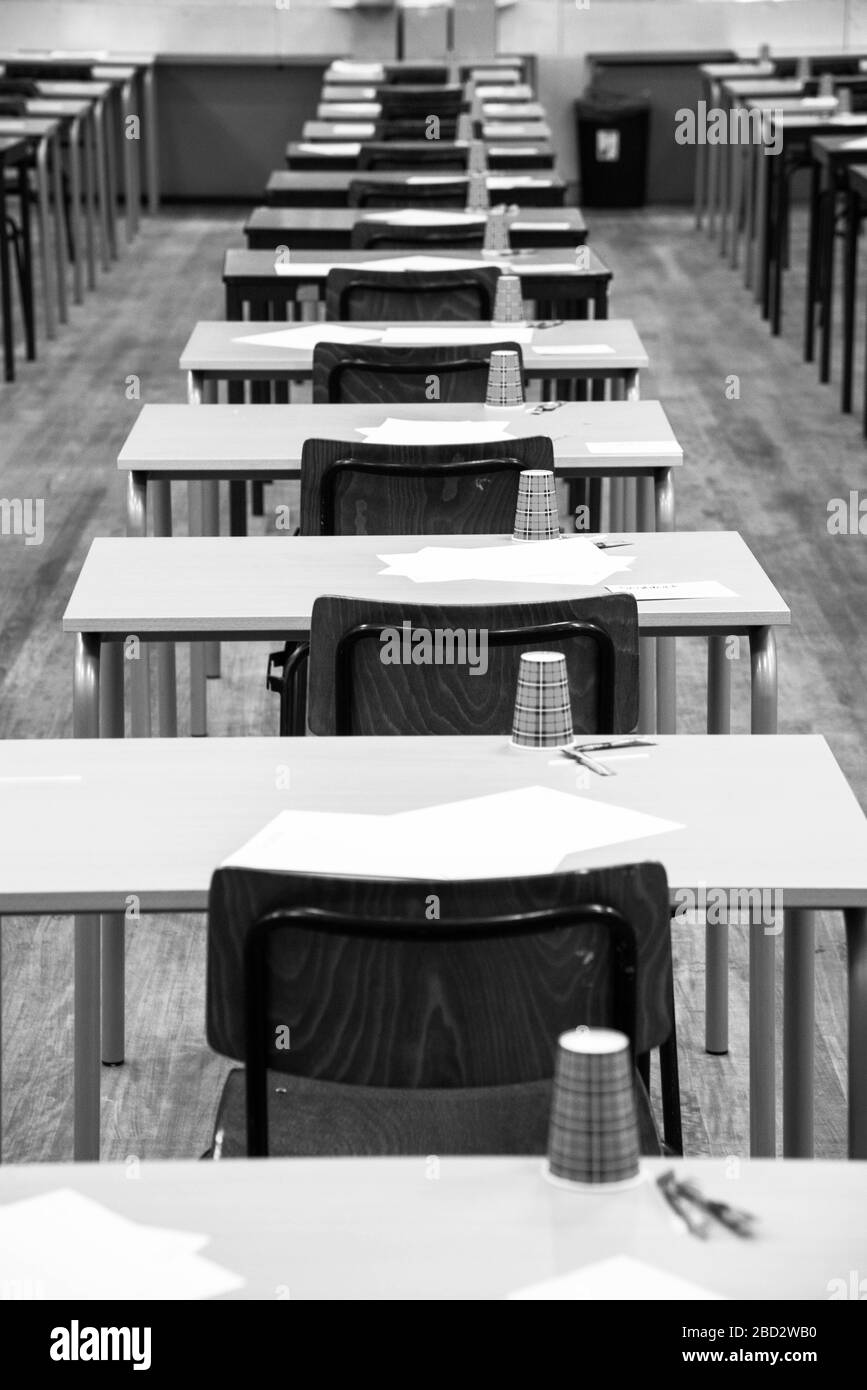 rows of empty tables and chairs in exam room at highschool in black and white Stock Photo