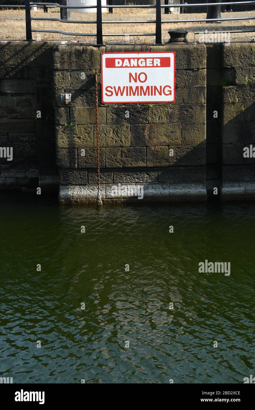 A danger no swimming sign on the wall of a harbour Stock Photo