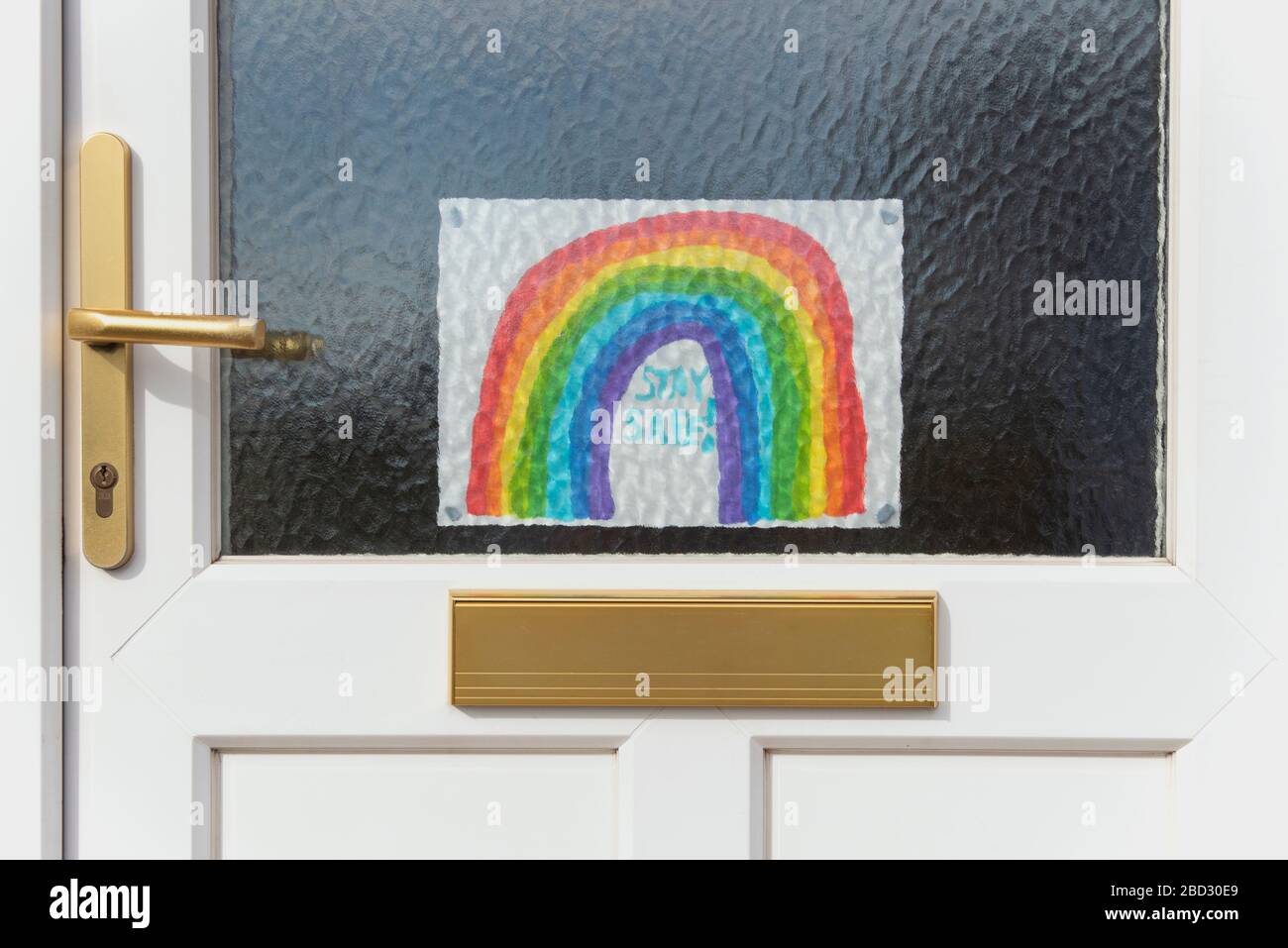 Drawing of a rainbow stuck to a front door during the Covid-19 pandemic of 2020, encouraging people to stay safe by staying at home, by Anna Anderson Stock Photo