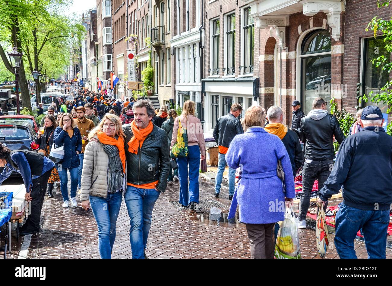 Amsterdam, Netherlands - April 27, 2019: People on the street wearing orange accessories celebrating the Kings day, Koningsdag, the birthday of the Dutch King Willem-Alexander. Overcrowded streets. Stock Photo