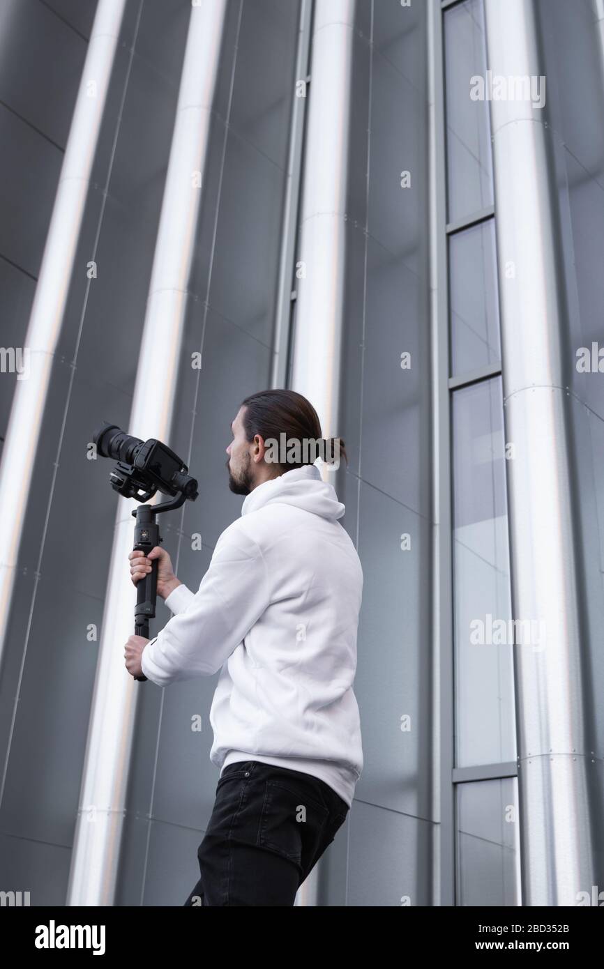 Young Professional videographer holding professional camera on 3-axis gimbal stabilizer. Pro equipment helps to make high quality video without Stock Photo