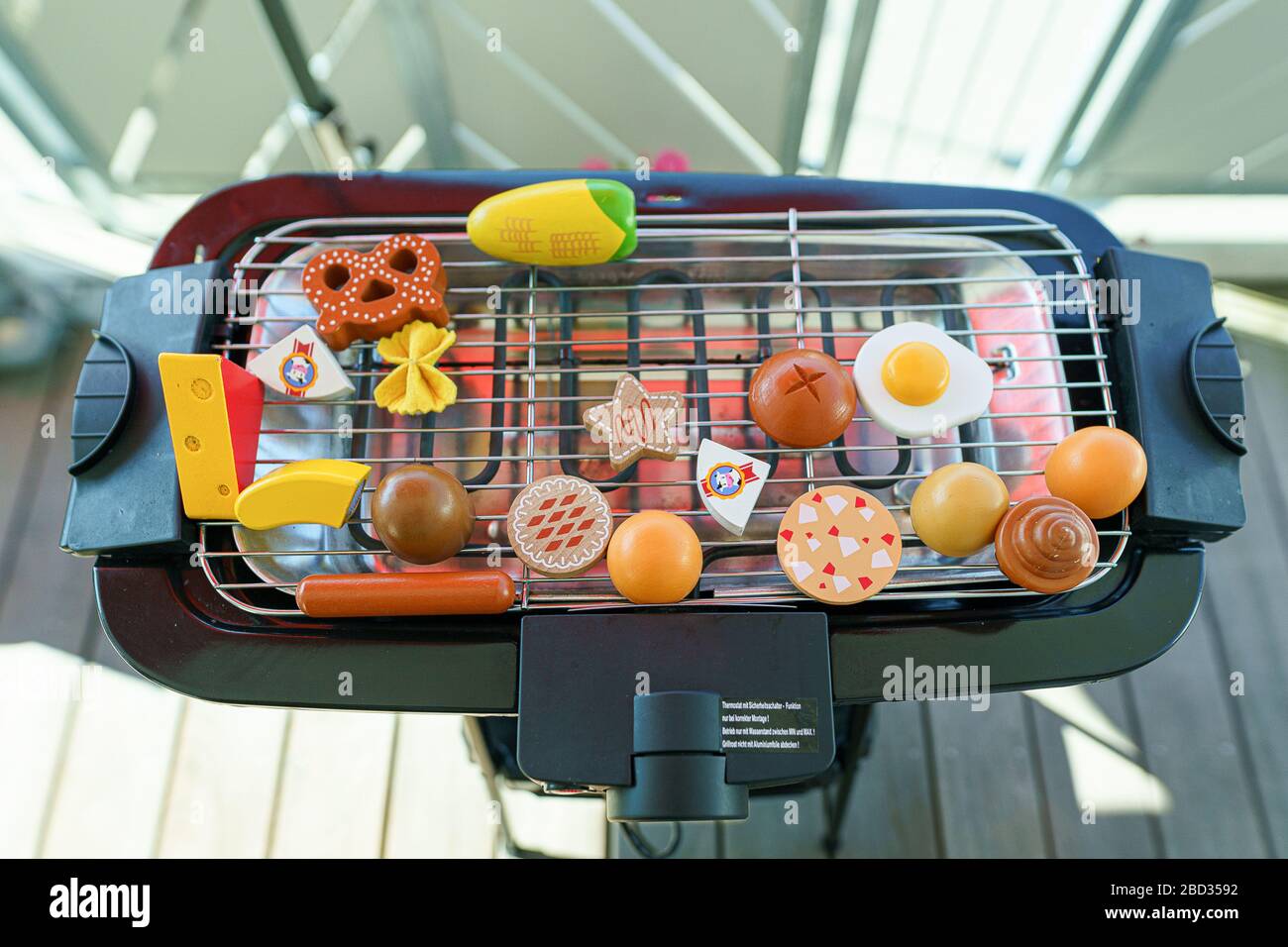 An electronic grill at the balcony full reserved with toy vegetables
