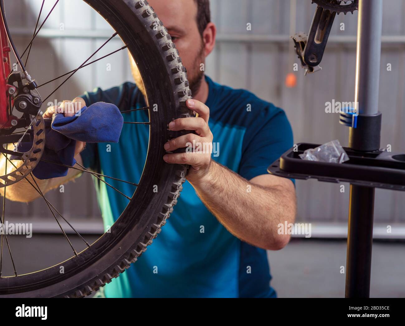 Mechanic in a bicycle repair shop oiling the chain of a bike. Man