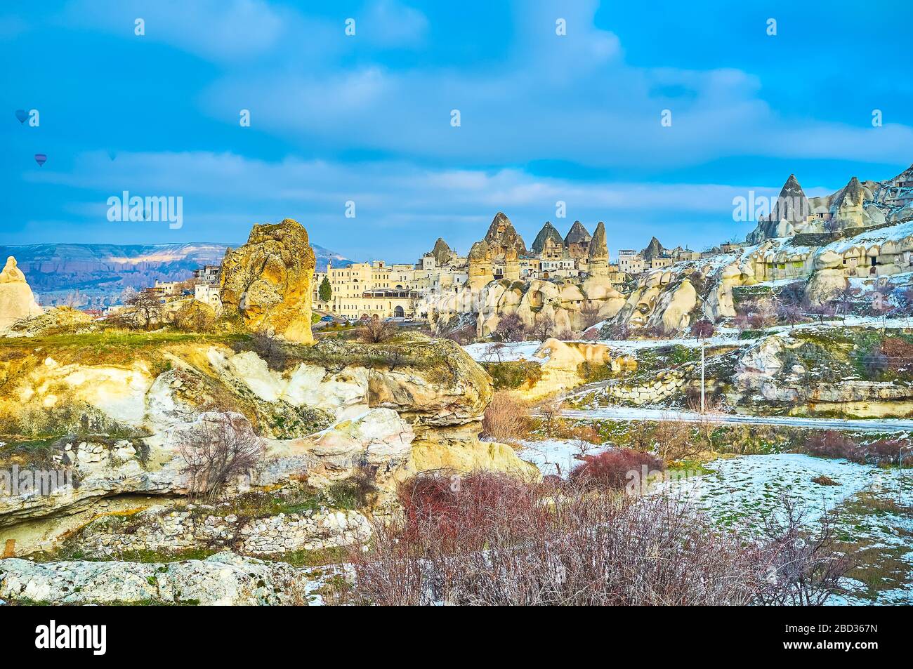The view on unique rocky  landscape of Goreme with its traditional stone housing and hot air balloons in the sky, Cappadocia, Turkey Stock Photo