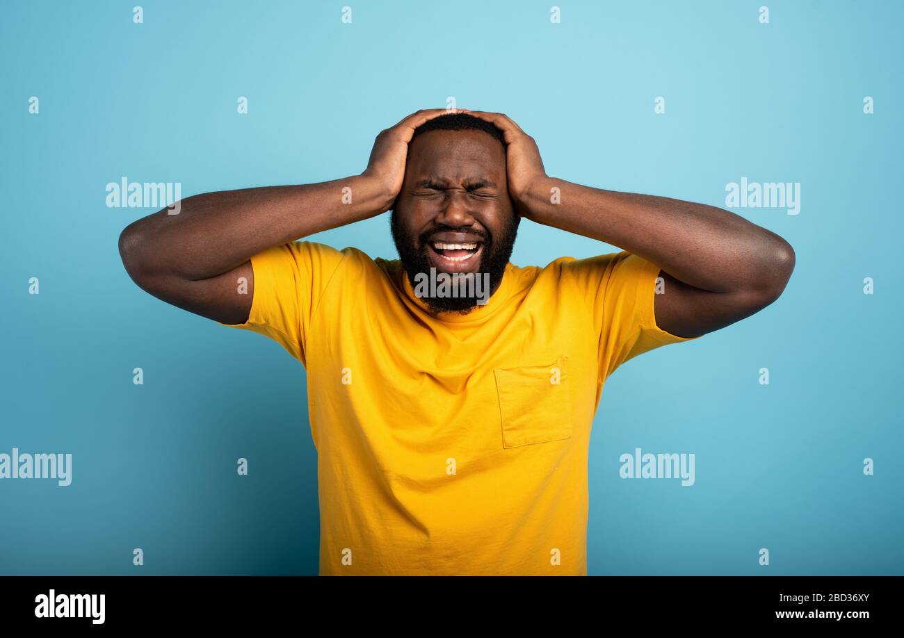 Sad and desperate expression of a boy who is scared to catch the covid-19 coronavirus. Cyan background. Stock Photo