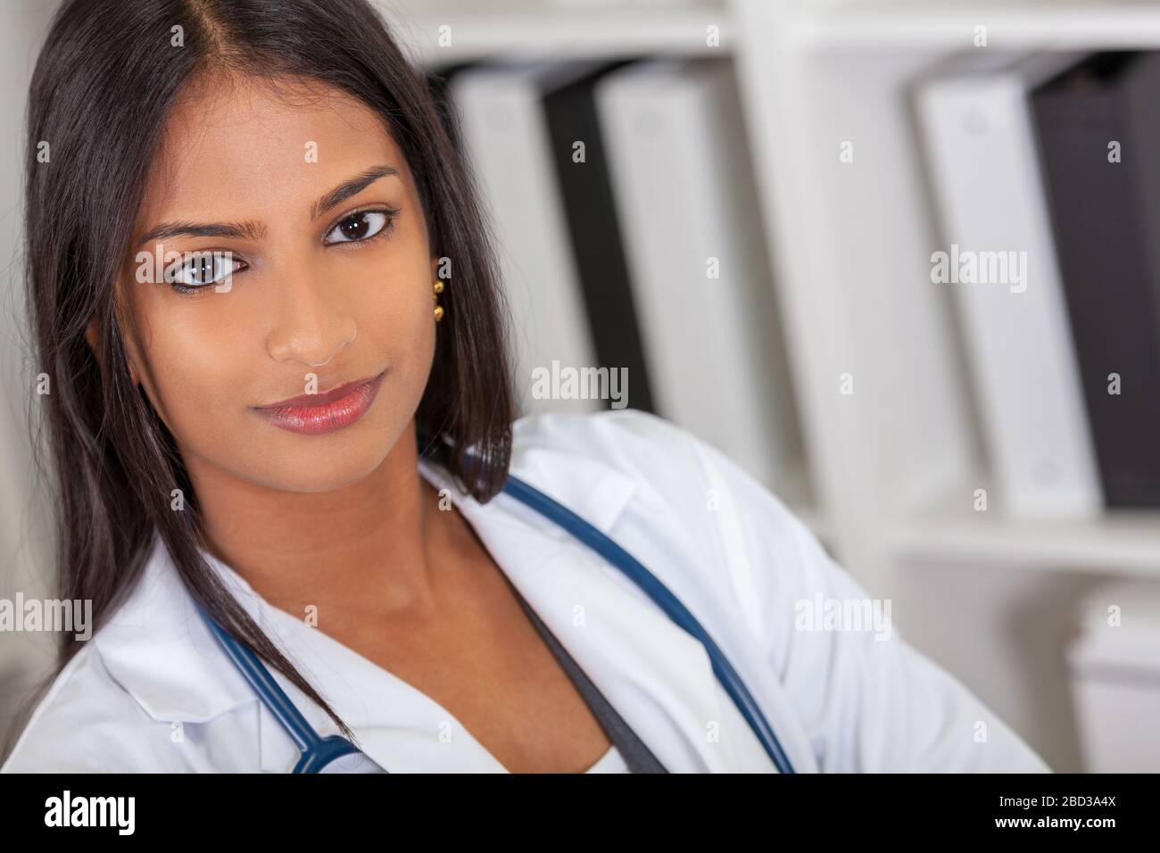 An Indian Asian female medical doctor in a hospital office happy and smiling with stethoscope Stock Photo